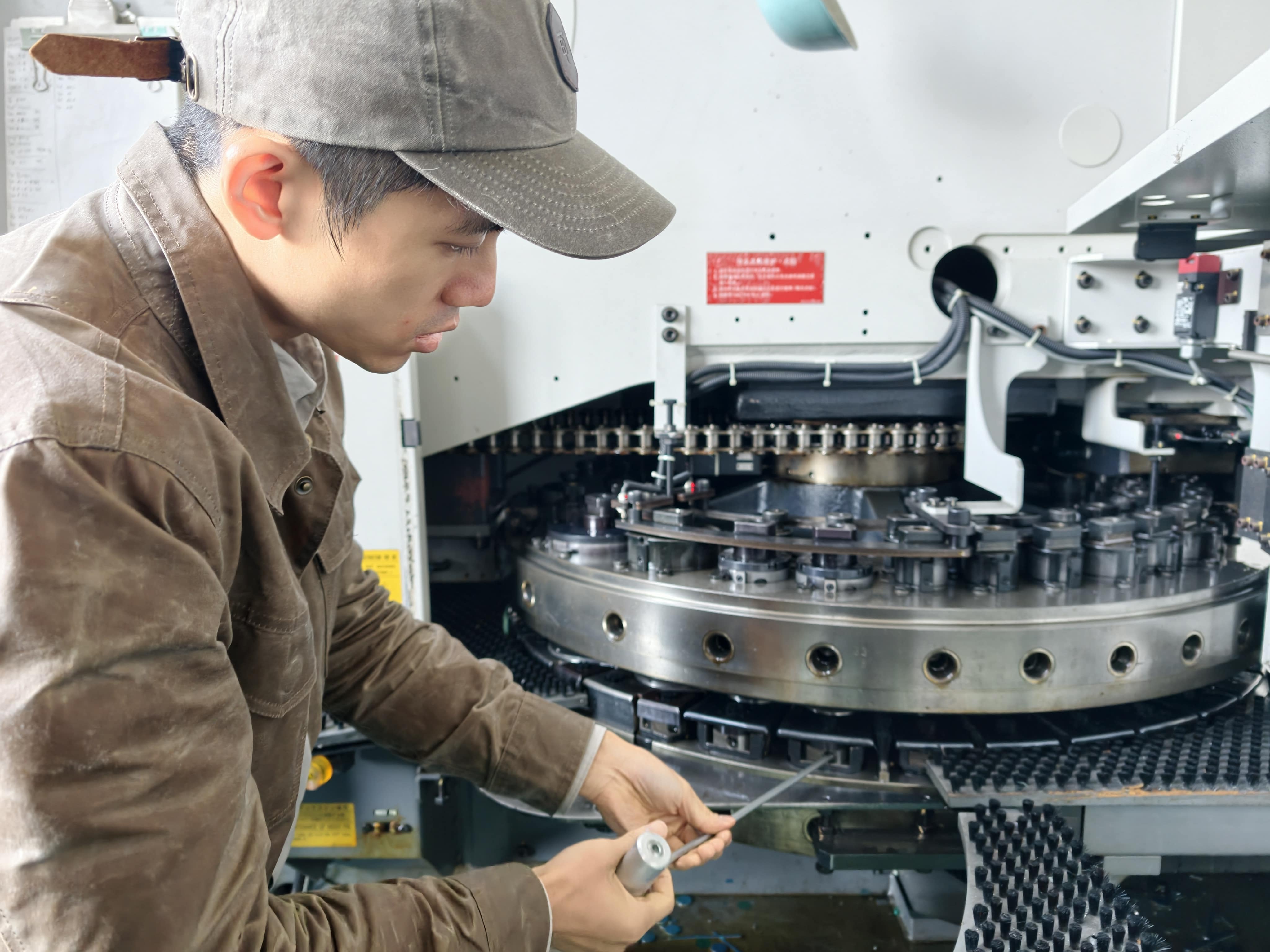 Bert working hands-on beside an NCT turret punch machine on a sheet metal factory floor.
