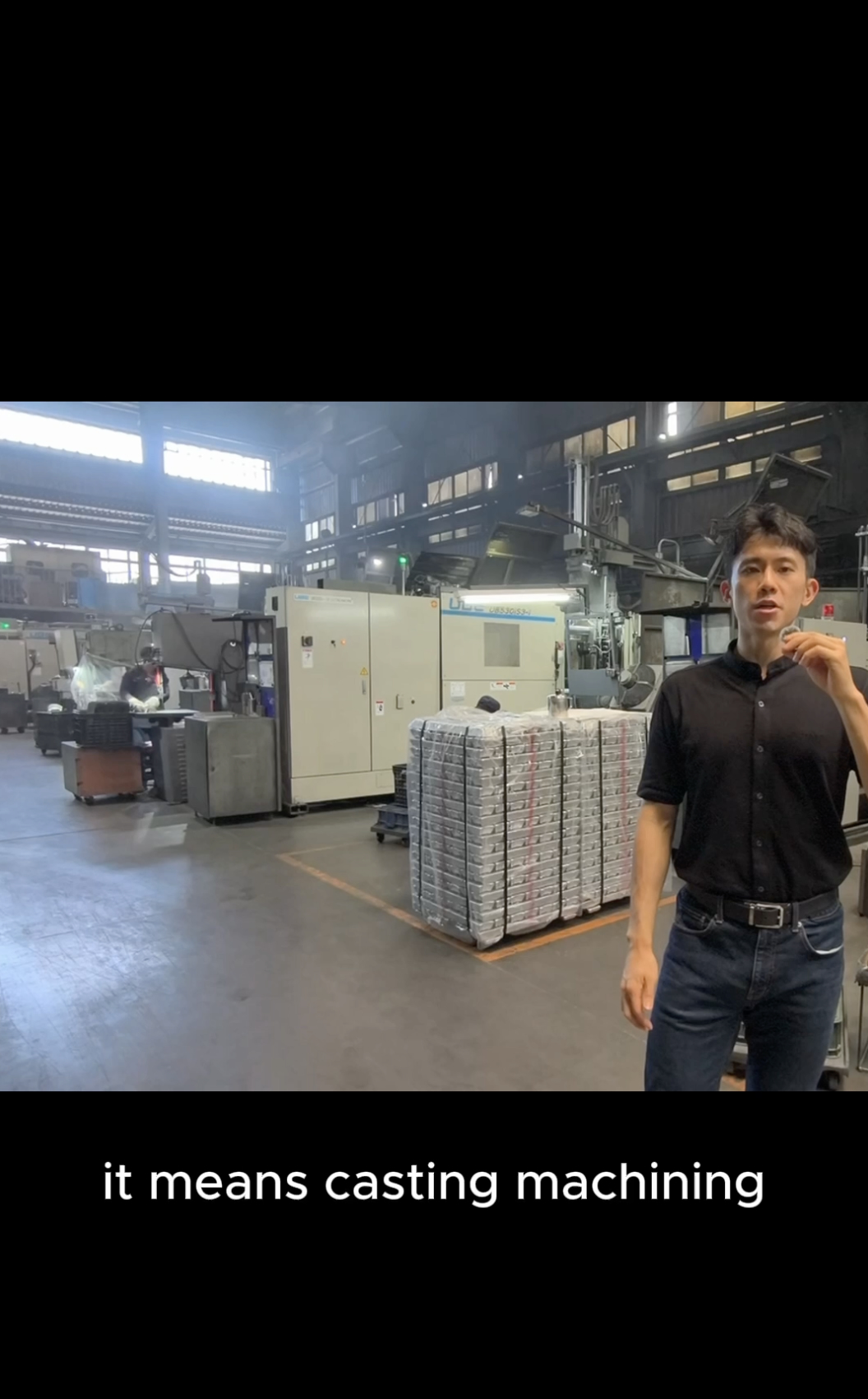 Bert on a die-casting factory floor beside stacked aluminum ingots.